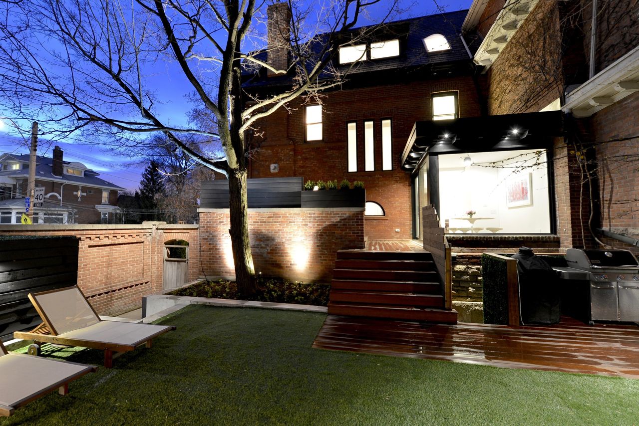 Evening view of the custom multi-level cedar deck featuring integrated lighting, creating a luxurious outdoor dining and entertainment space.
