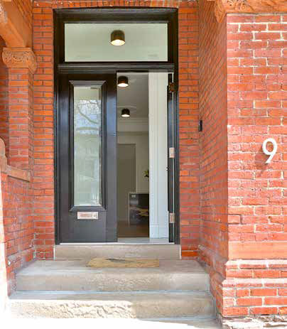 Contemporary glass entrance door with sleek design, perfectly integrated with the brick surround and featuring the prominent house number '9'.