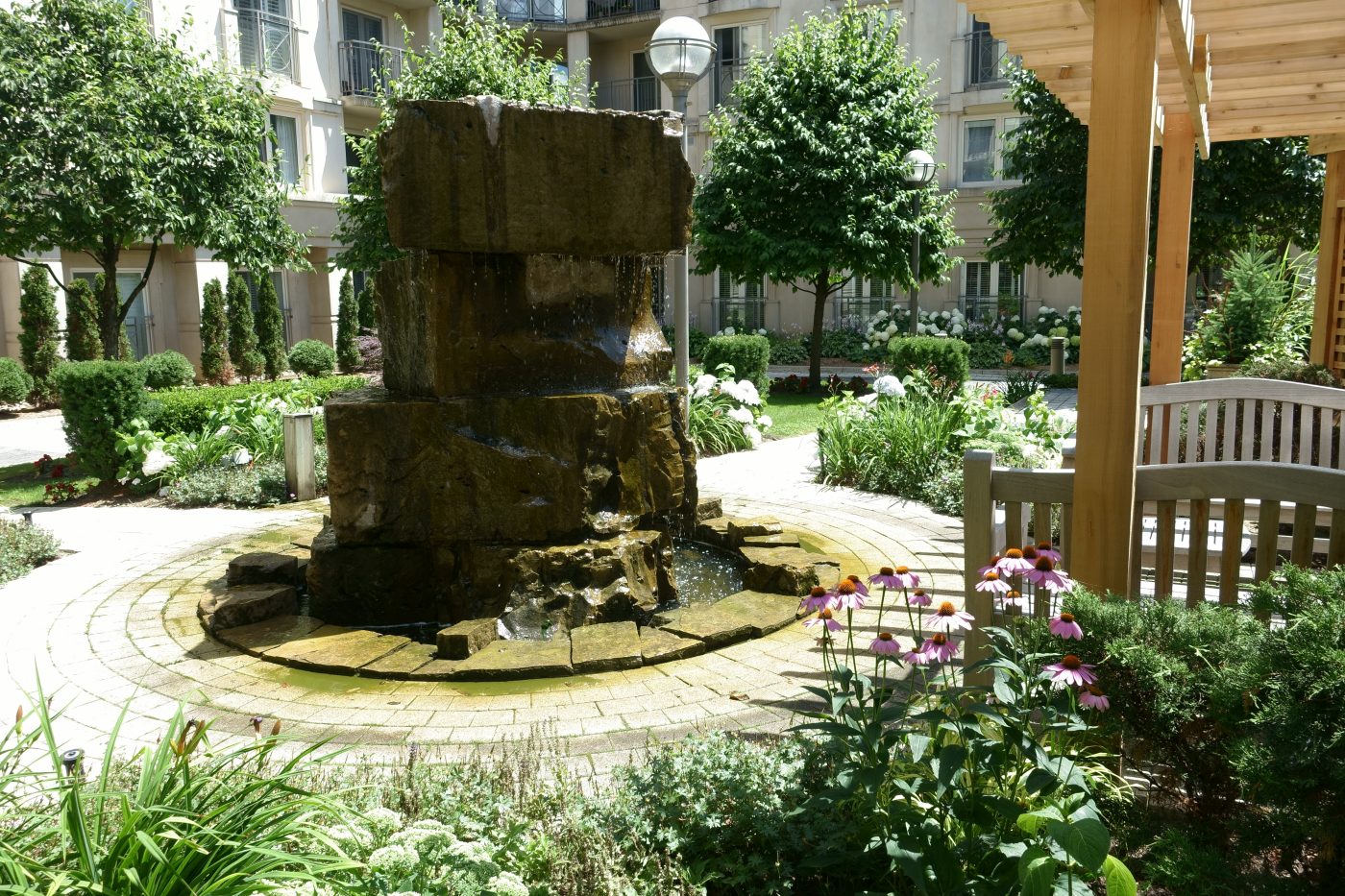 Stone water feature surrounded by seating area and gardens provide an area for residents to interact and experience nature within an urban environment 