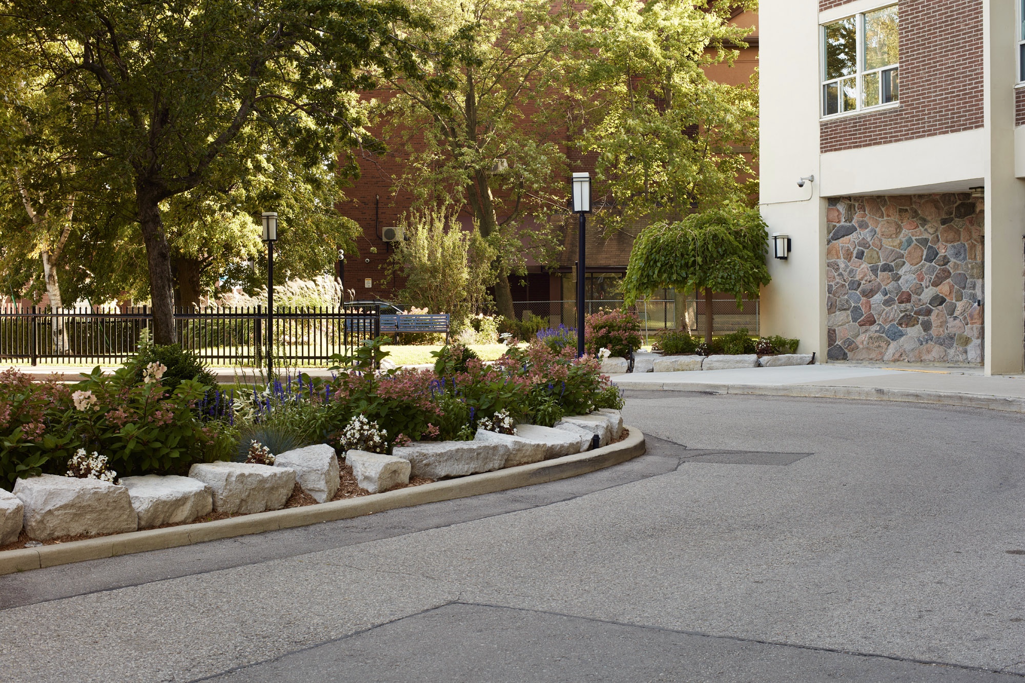 naturalized stone surrounding garden bed style island in middle of driveway.