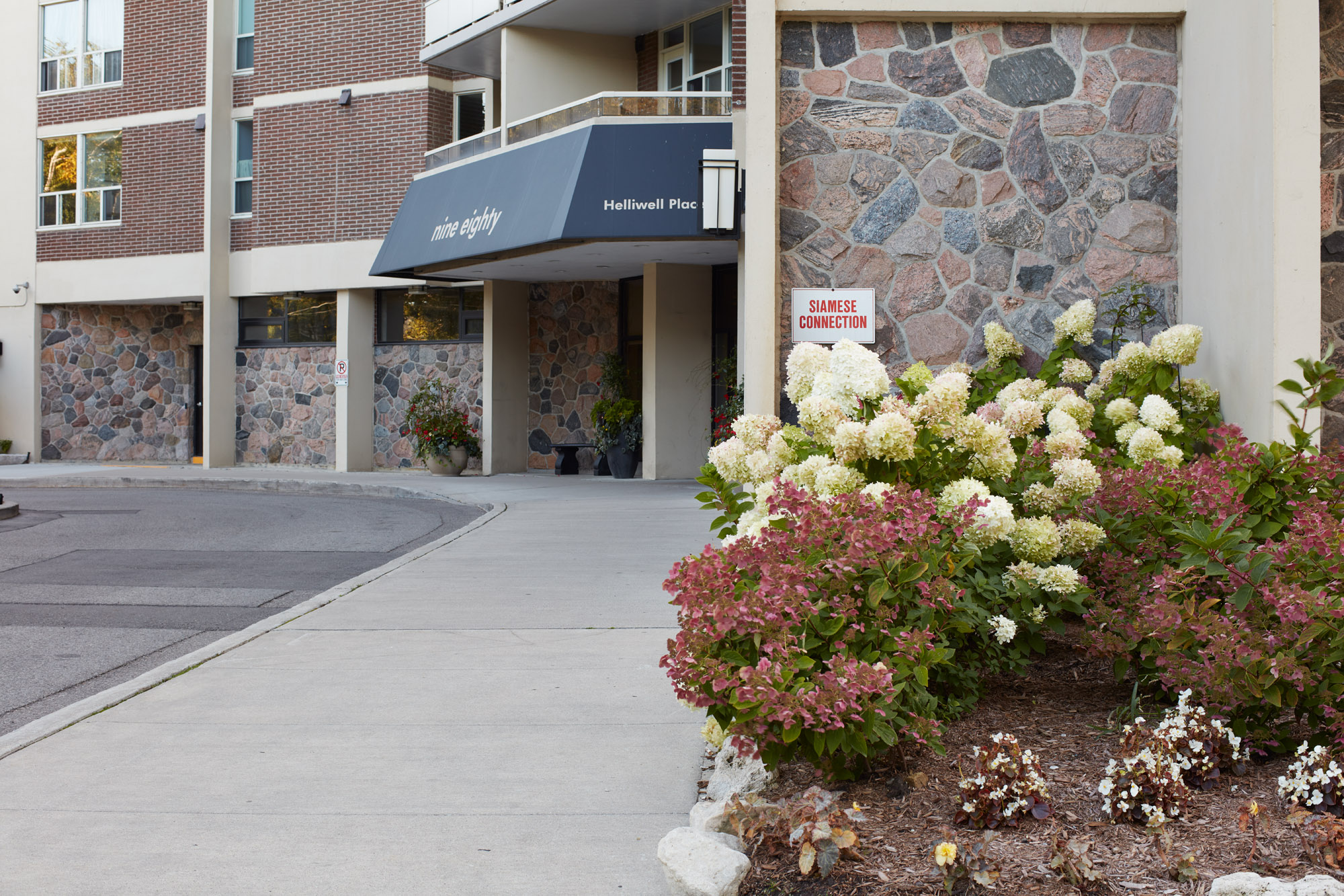 Flower Bed on rightside of building showcases unique perennial colors and natural stone building exterior