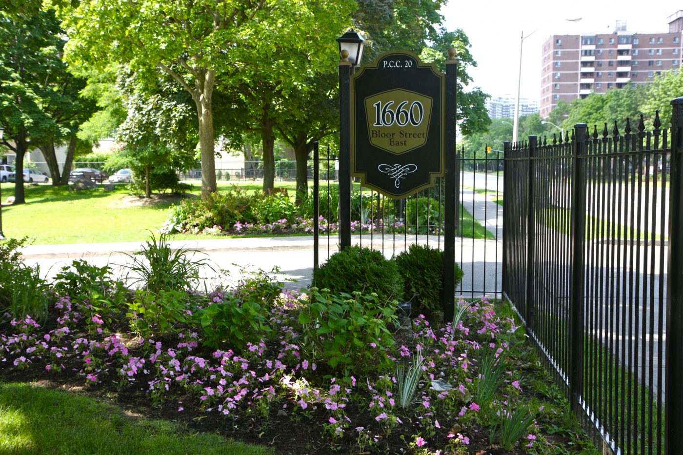 wrought iron fence and perennial garden beds showcases property sign