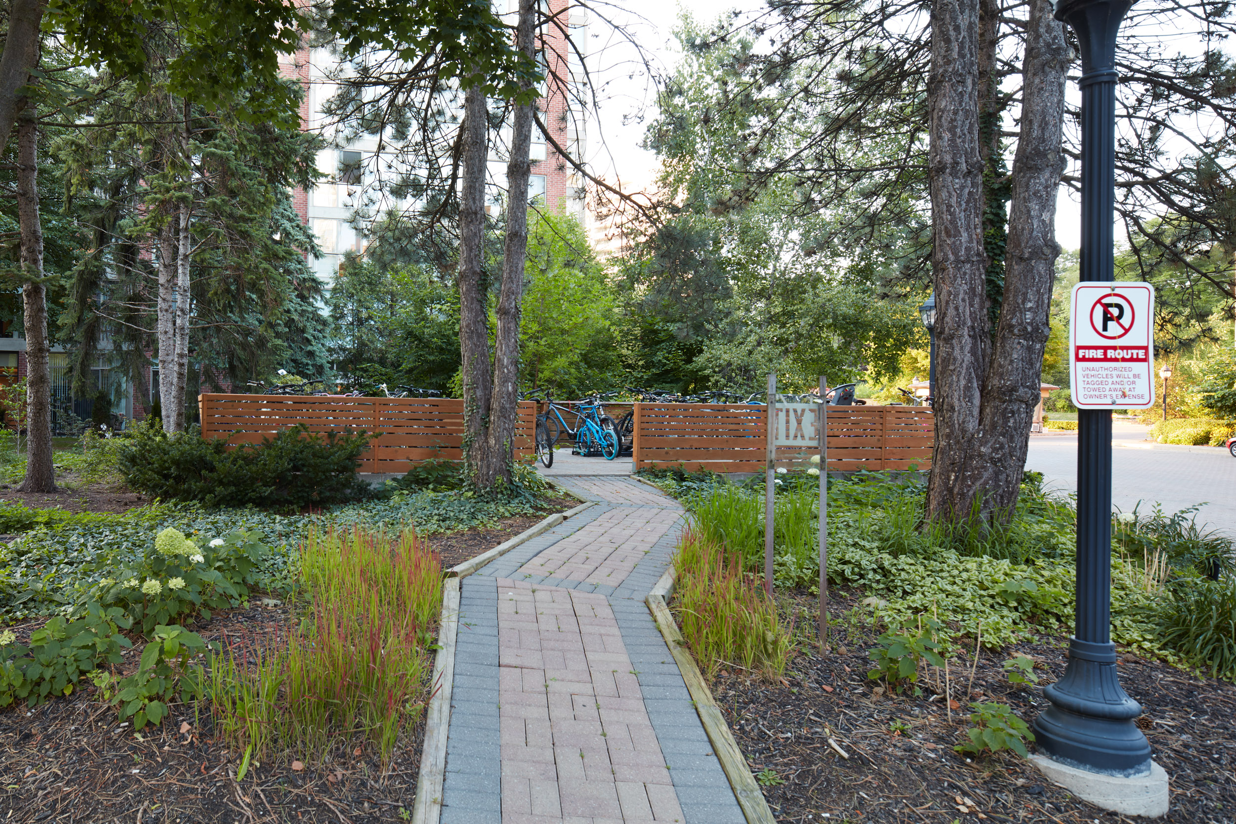 Stone Walkway through the back of the property. Garden beds and trees flank pathway