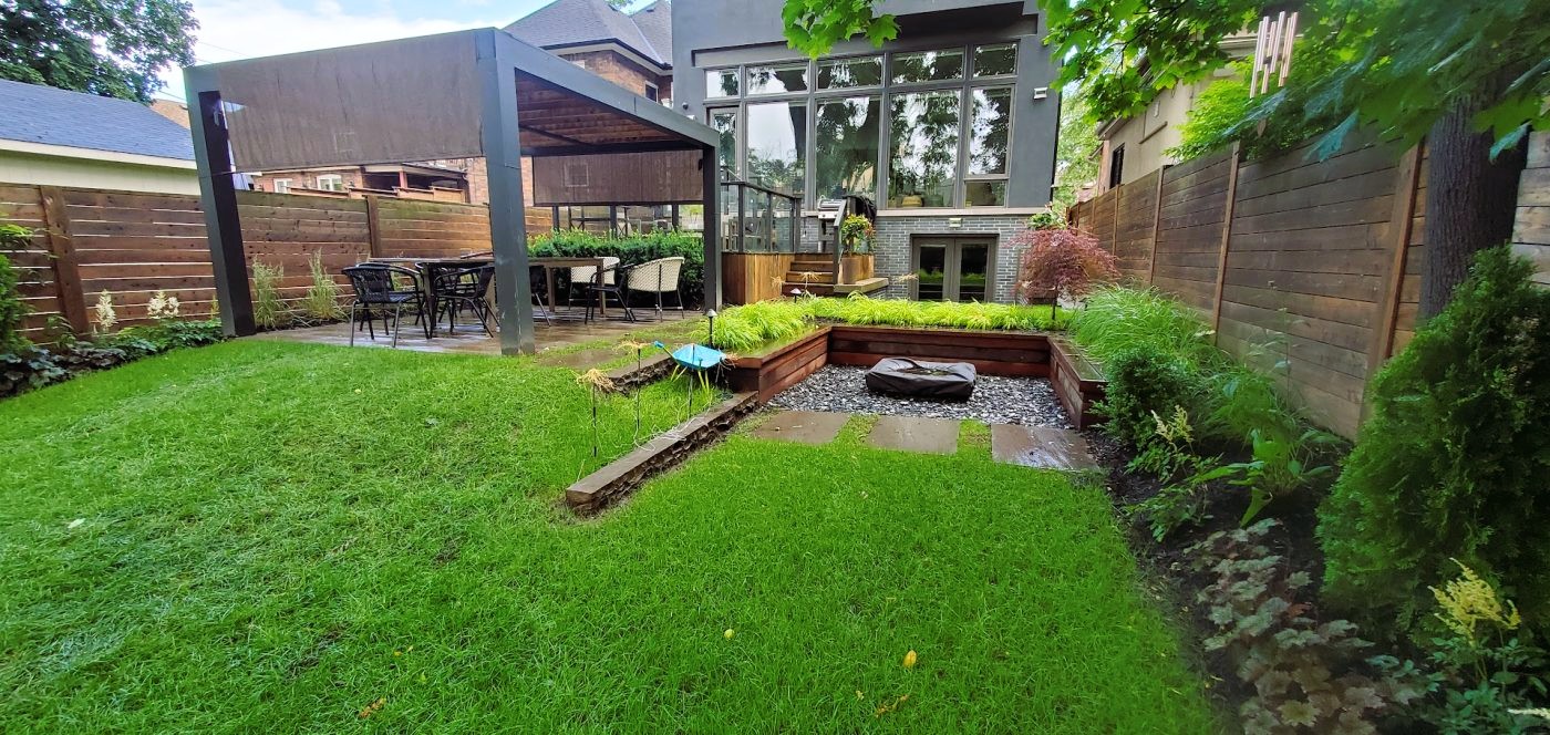 Lawn Space leading up to custom built fire pit with garden beds along the fence on the right