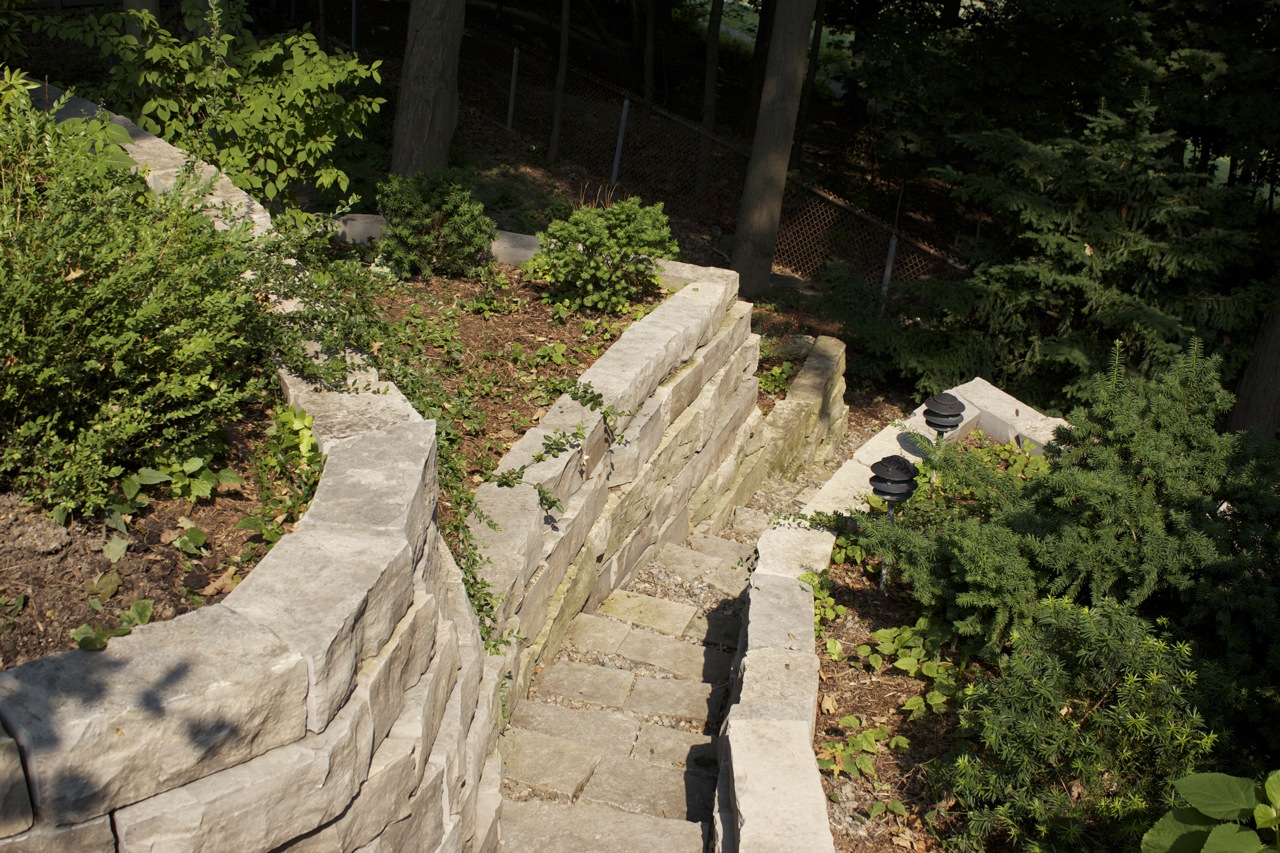 massive stone stairs built into natural hill with retaining wall containing flower beds along the sides