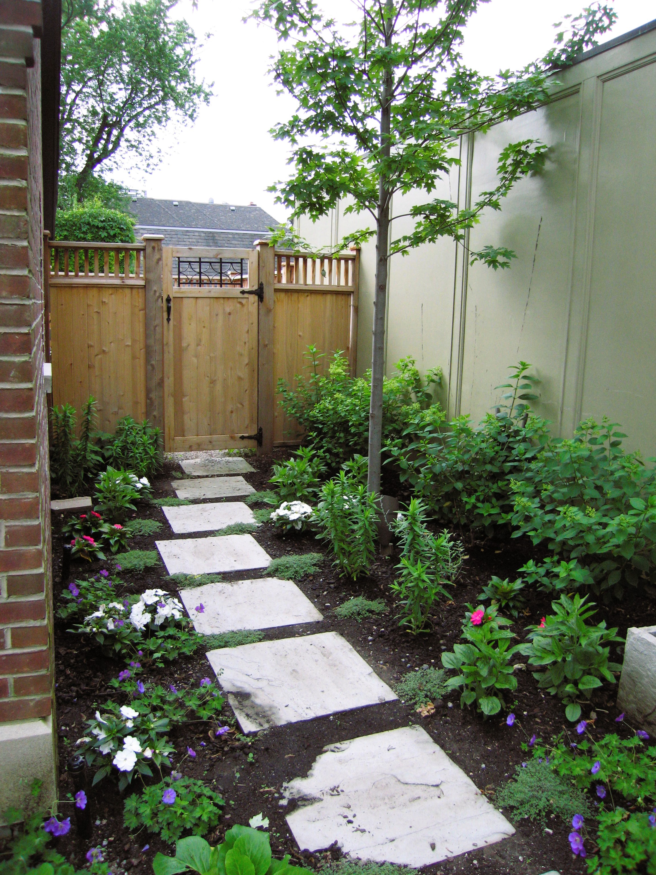 Stone Stepping stones placed along garden beds leading up to back gate