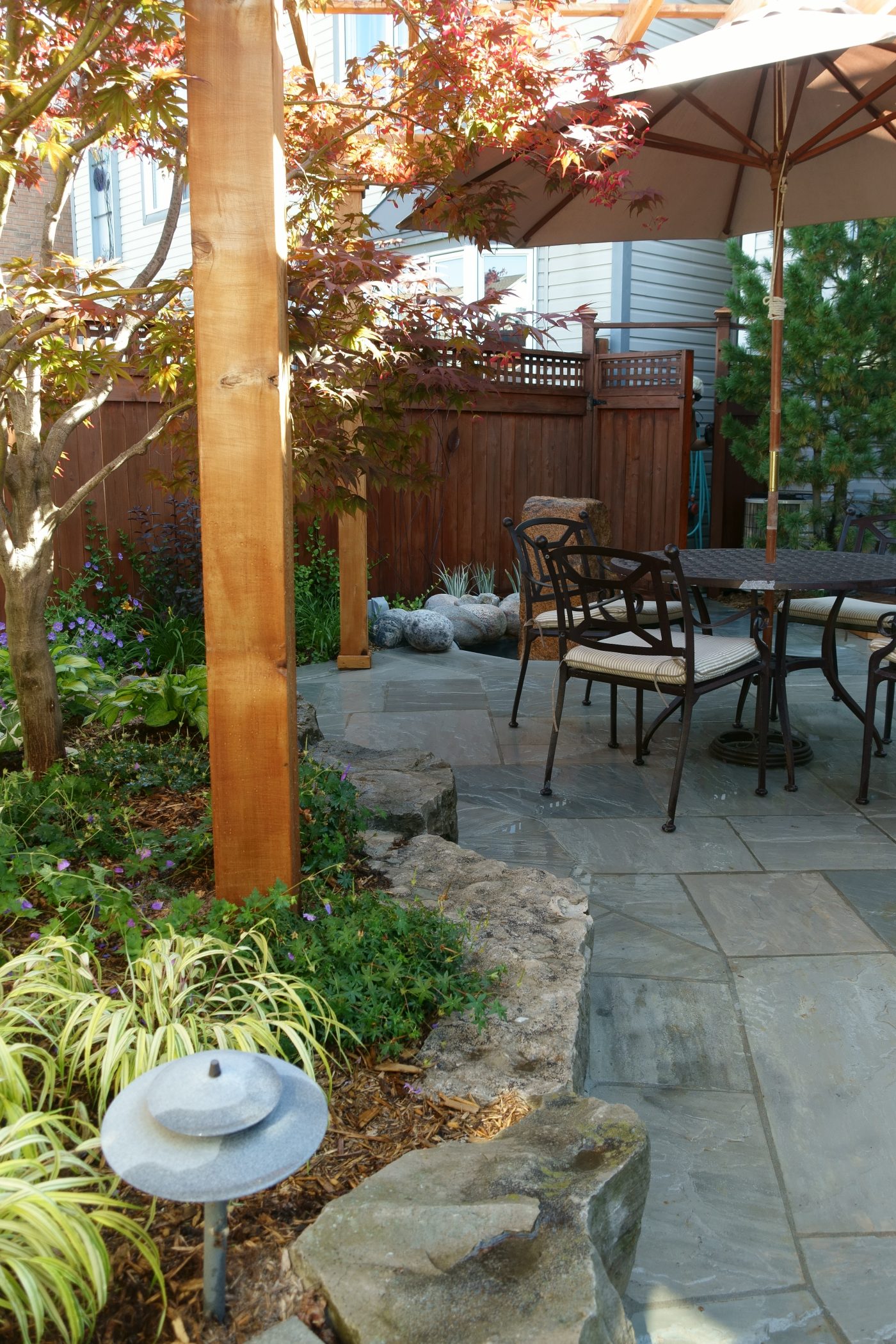 Pergola and stonework next to stone retaining wall garden bed