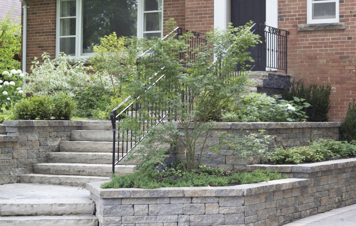 interlock stone retaining walls with stone slab staircase built with a wrought iron railing