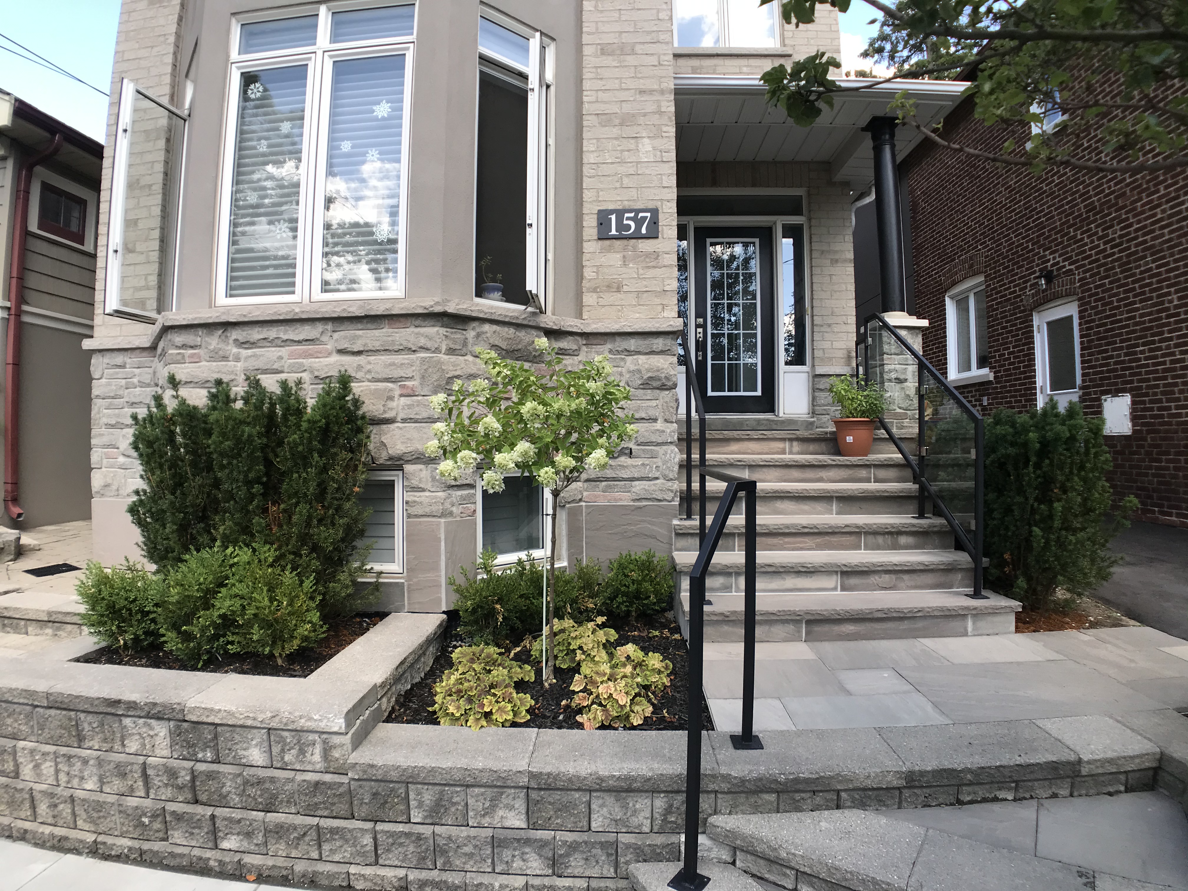 retaining wall garden beds next to large stone staircase to front of this residential property