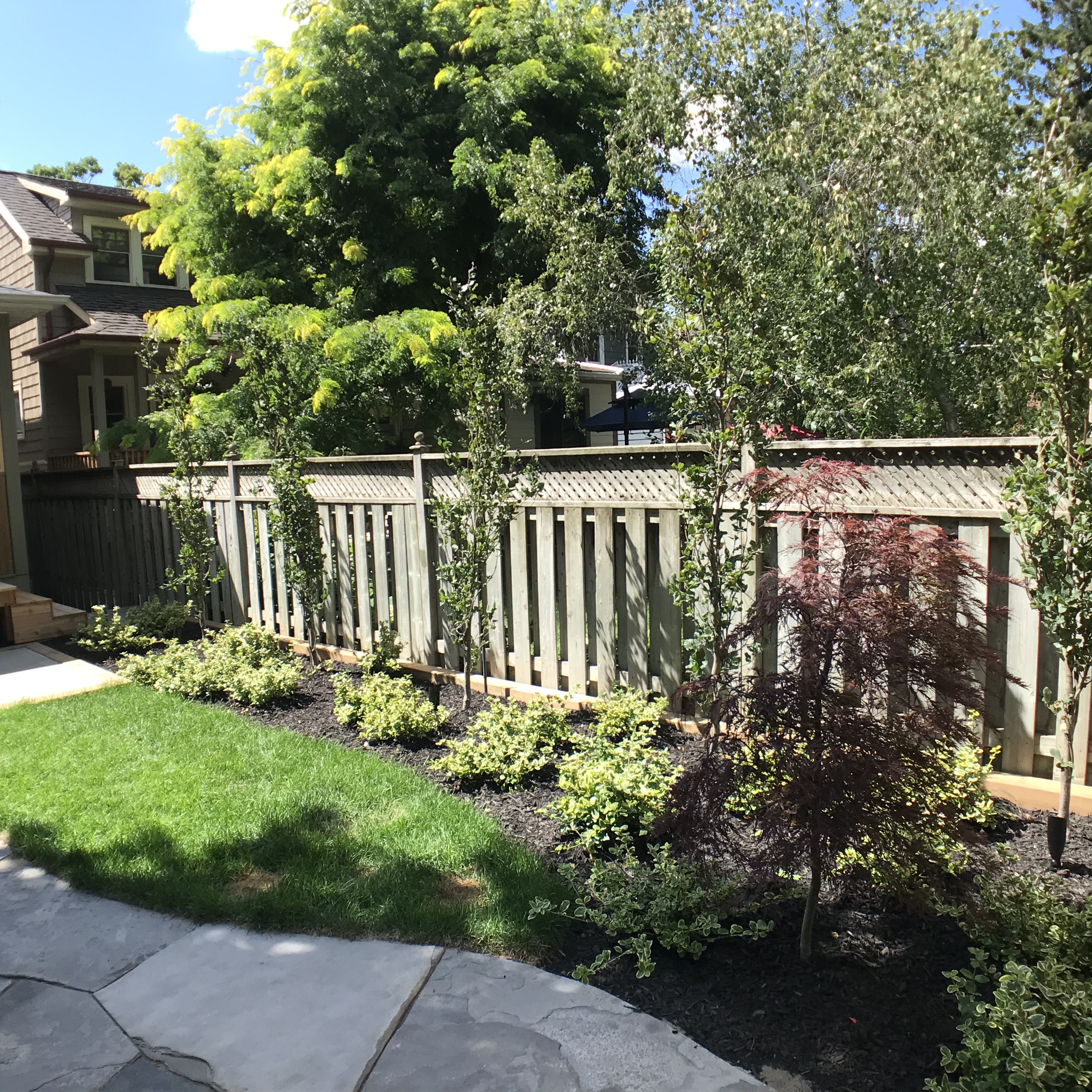 Lawn space and garden beds alongside stone patio area