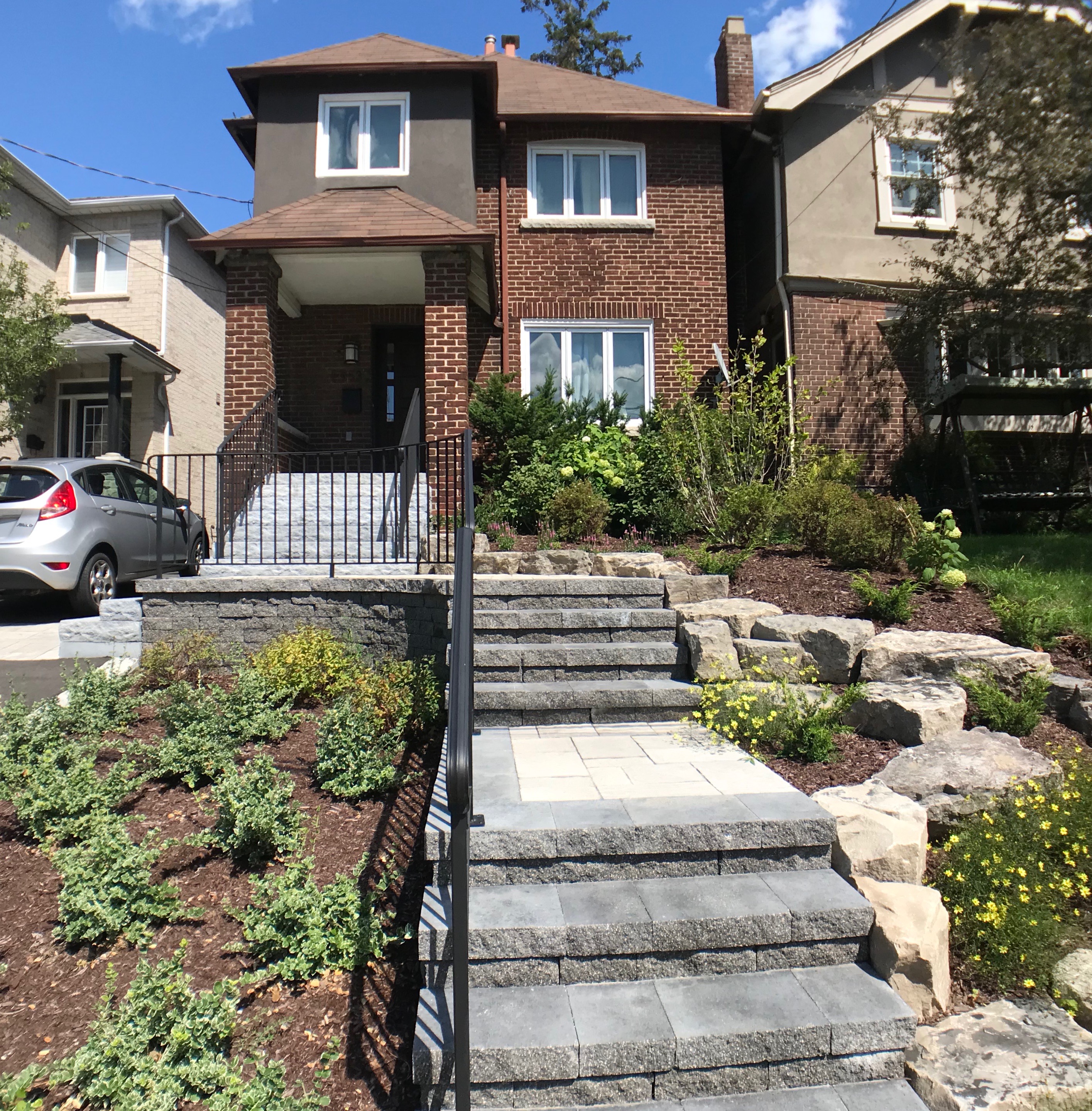 natural brown mulch perennial flower beds with natural stone stair case and black iron hand railing
