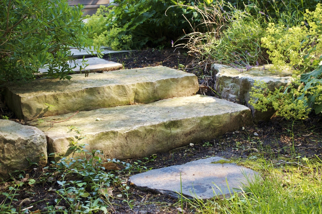 Natural stoe stairs leading to stone walkway with garden in the backl