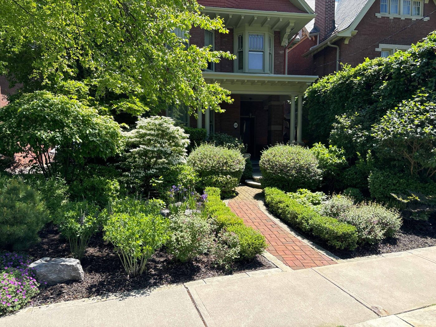massive gardens on either side of this brick interlock walkway to the front door
