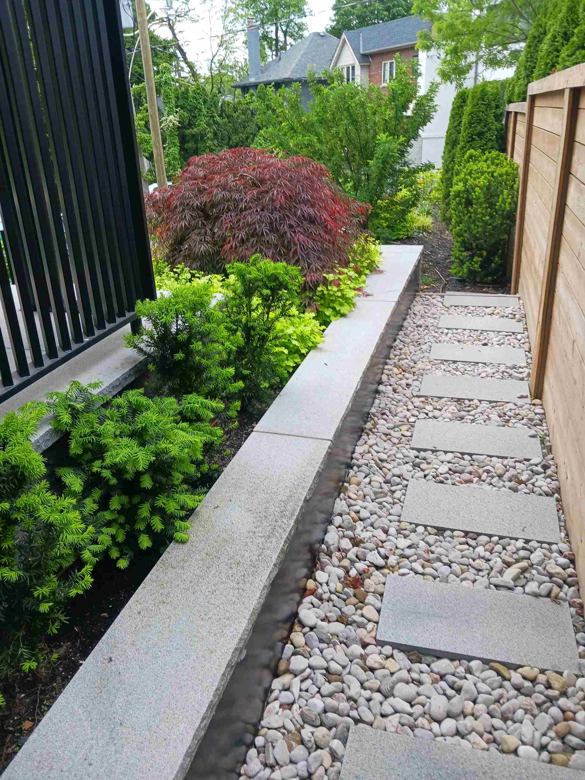 Stone walkway on the side of the property with gardens beds within a retaining wall