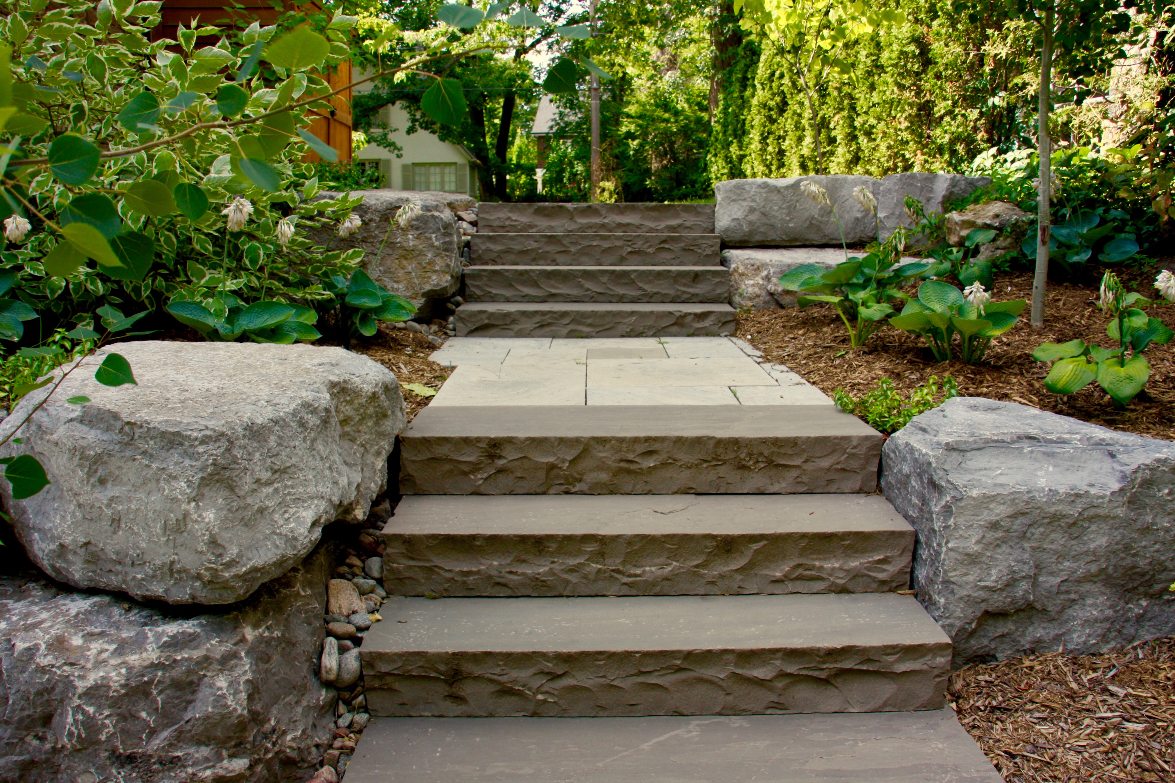Natural stone rocks fill gardens beds of natural brown mulch