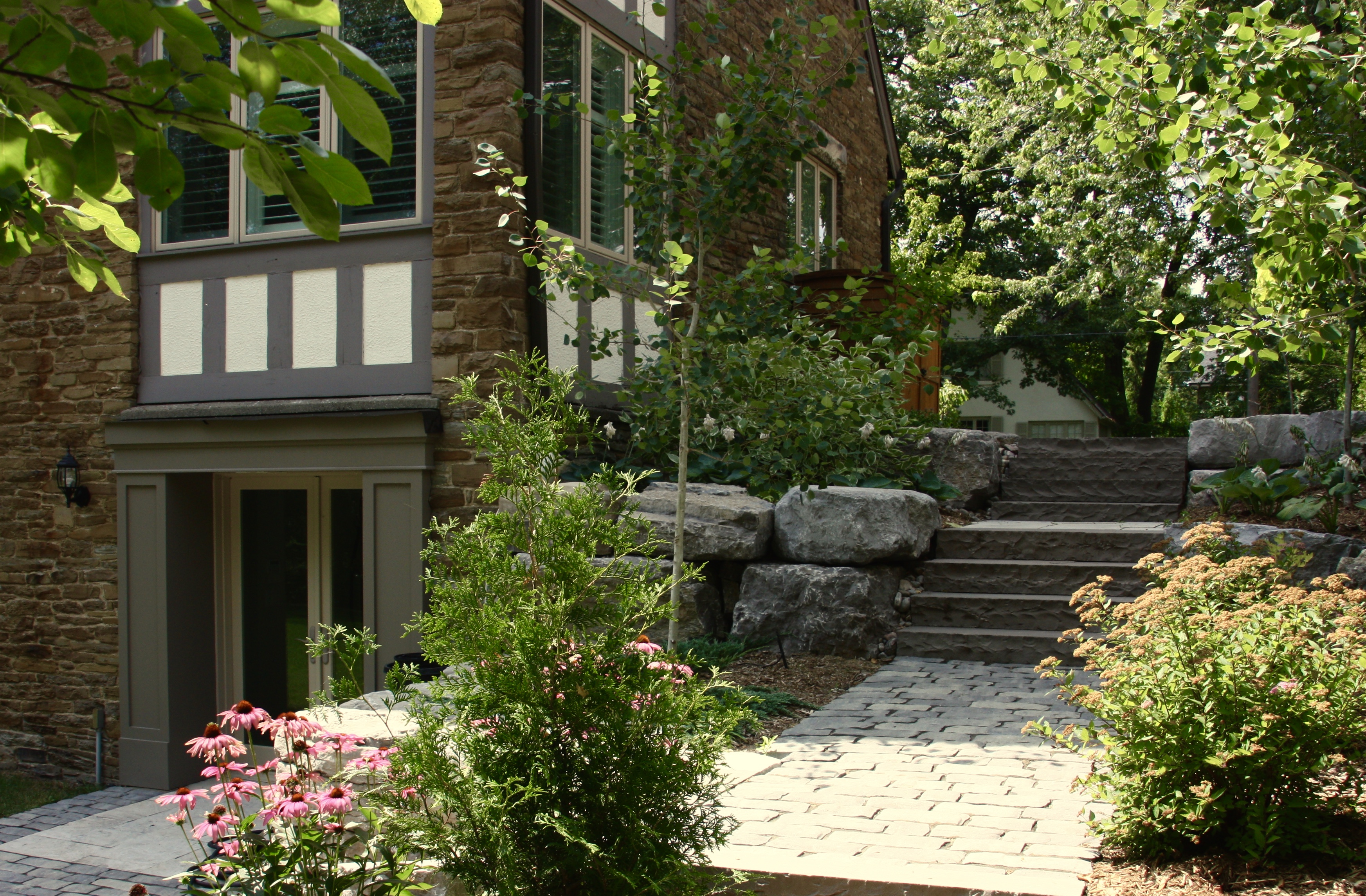 zoomed out backyard stairs showing evergreen trees and natural brown mulch garden beds