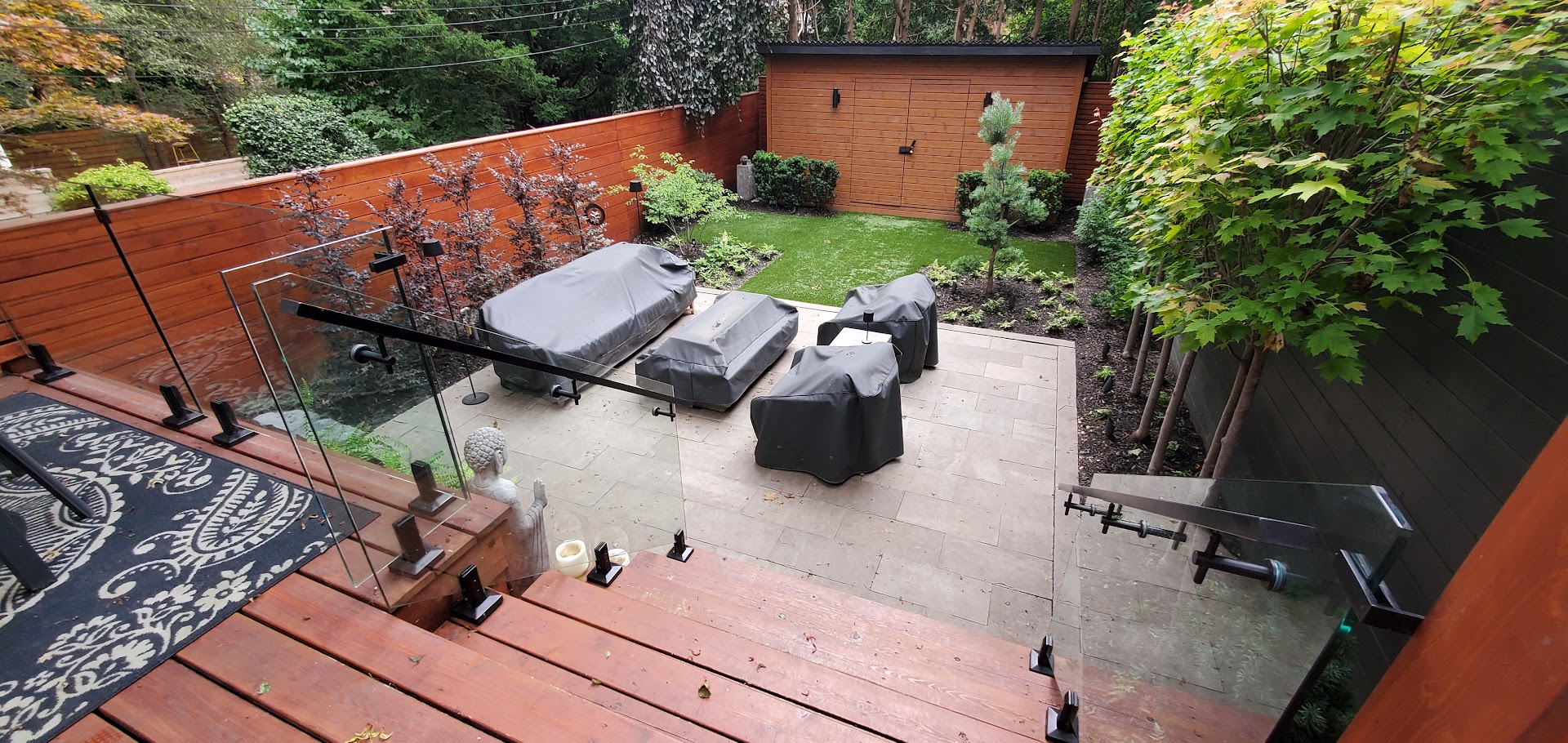 View looking from upper deck to lower patio. Showcasing new trees and outdoor spaces