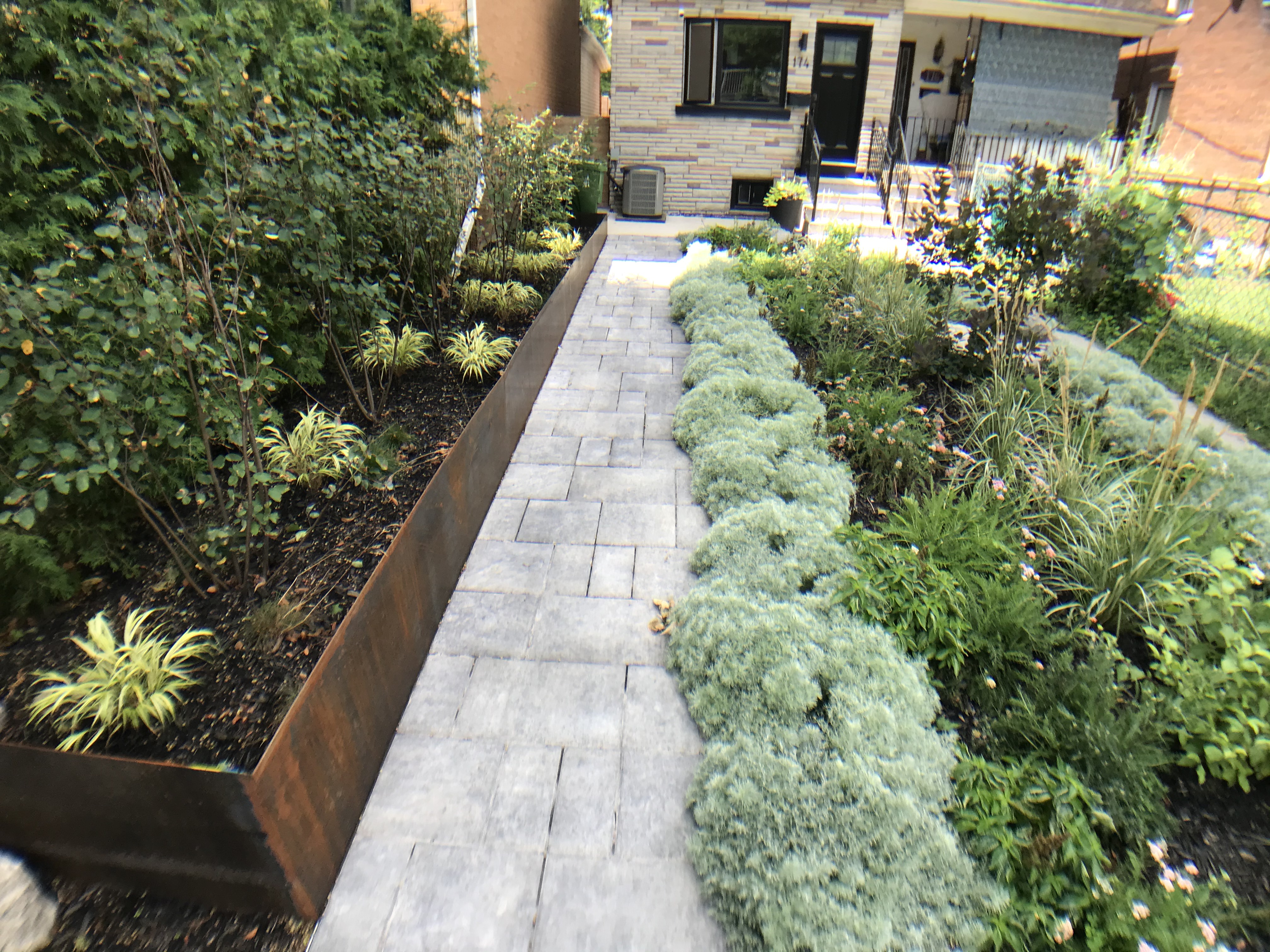 Copper Planters containing variety of perennials along stone pathway
