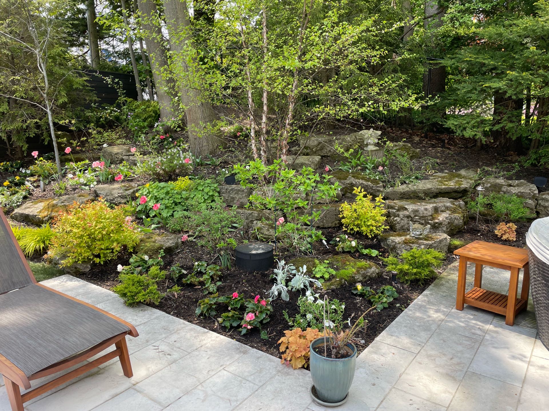 Large natural garden with mulch next to outdoor sun seating