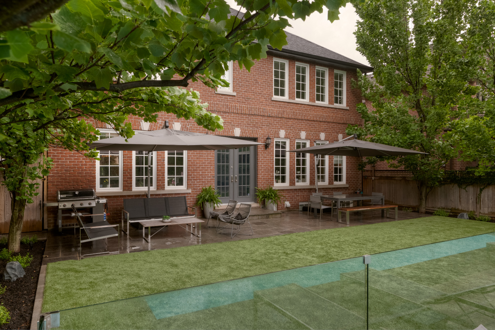 Backyard of astro turf with beds on both sides with Black Mulch