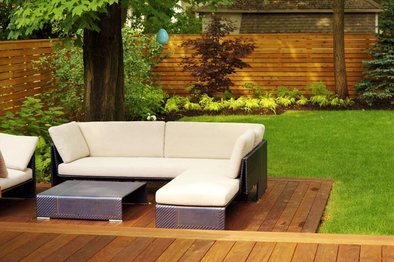 Outdoor couch furniture on wooden deck/patio leading up to lawn space
