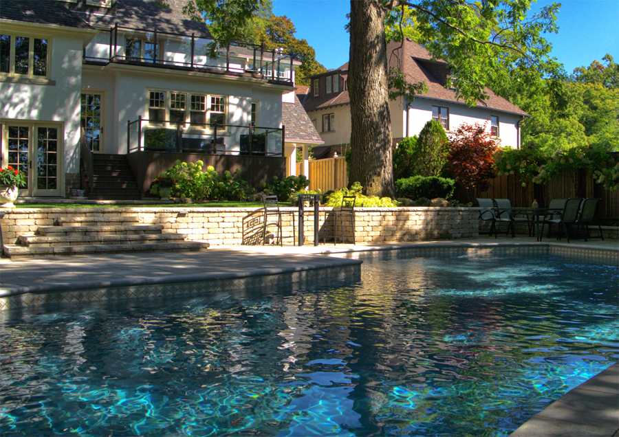 Backyard pool with custom stone wall and walkway around outdoor area