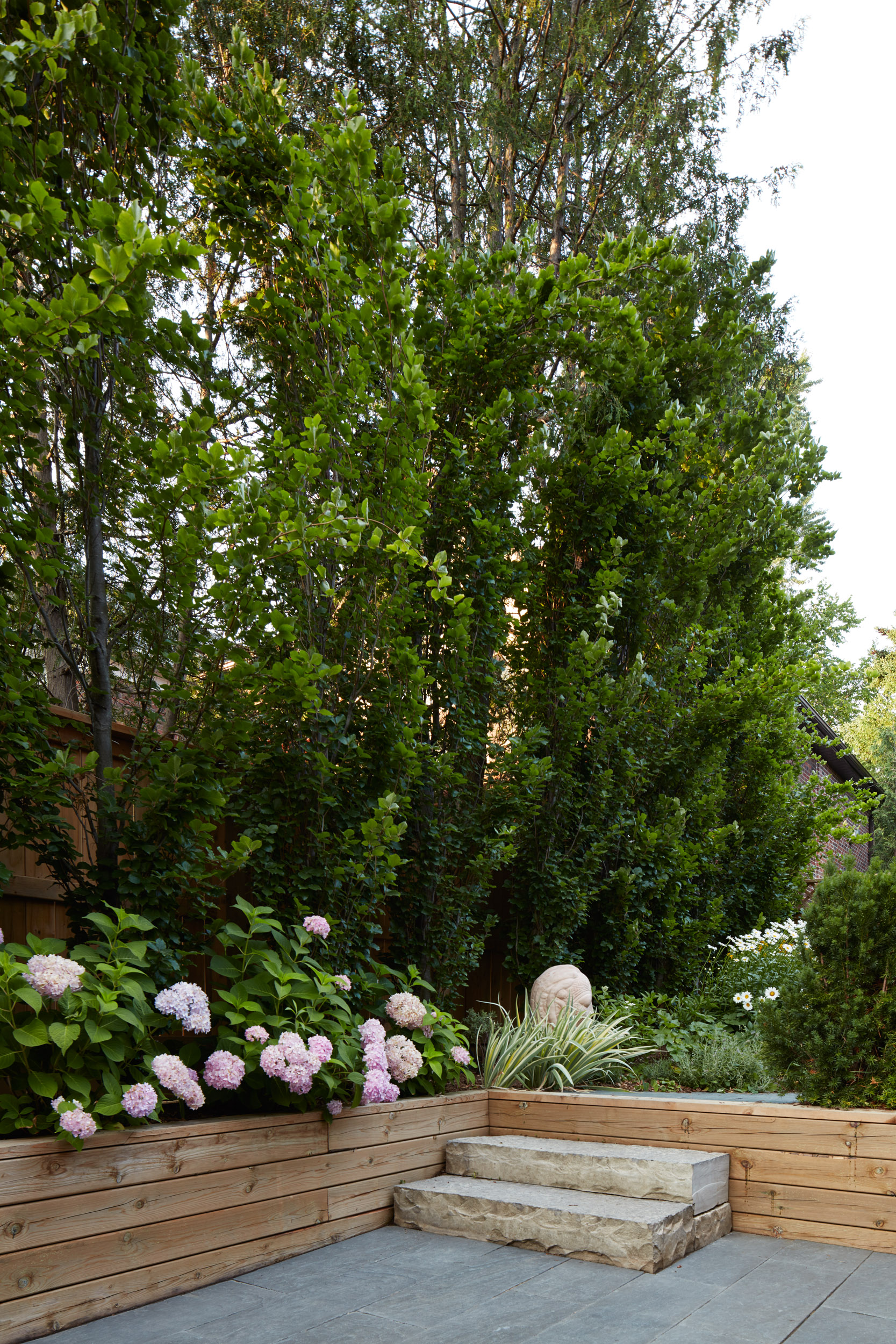 Vertical view of stone stepping area with statues and retaining wall garden beds