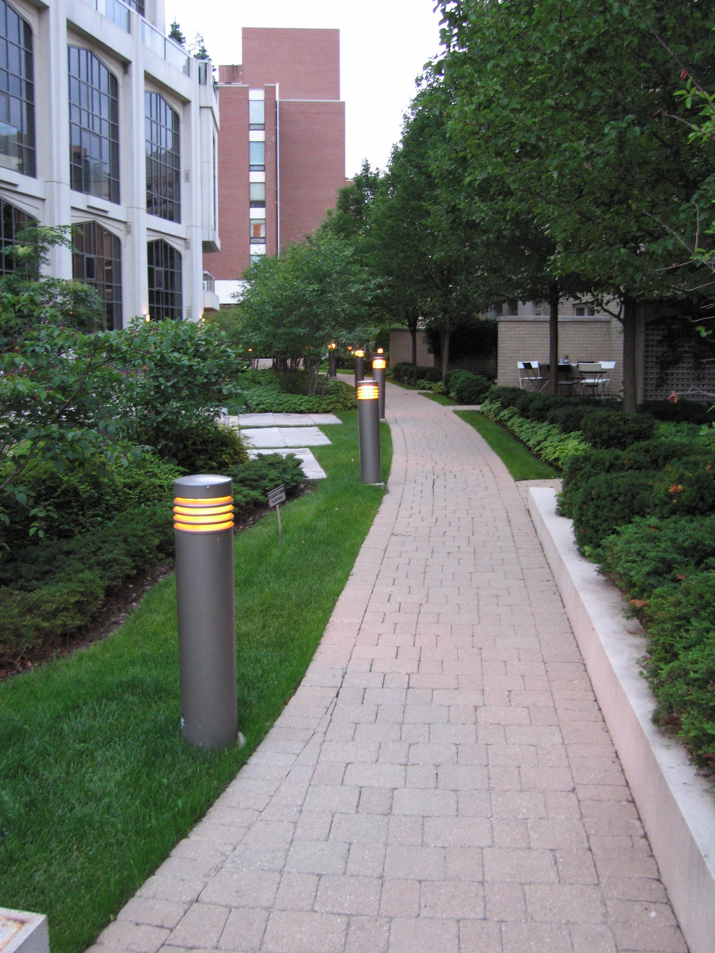 Lighting along path with well cut grass and garden beds