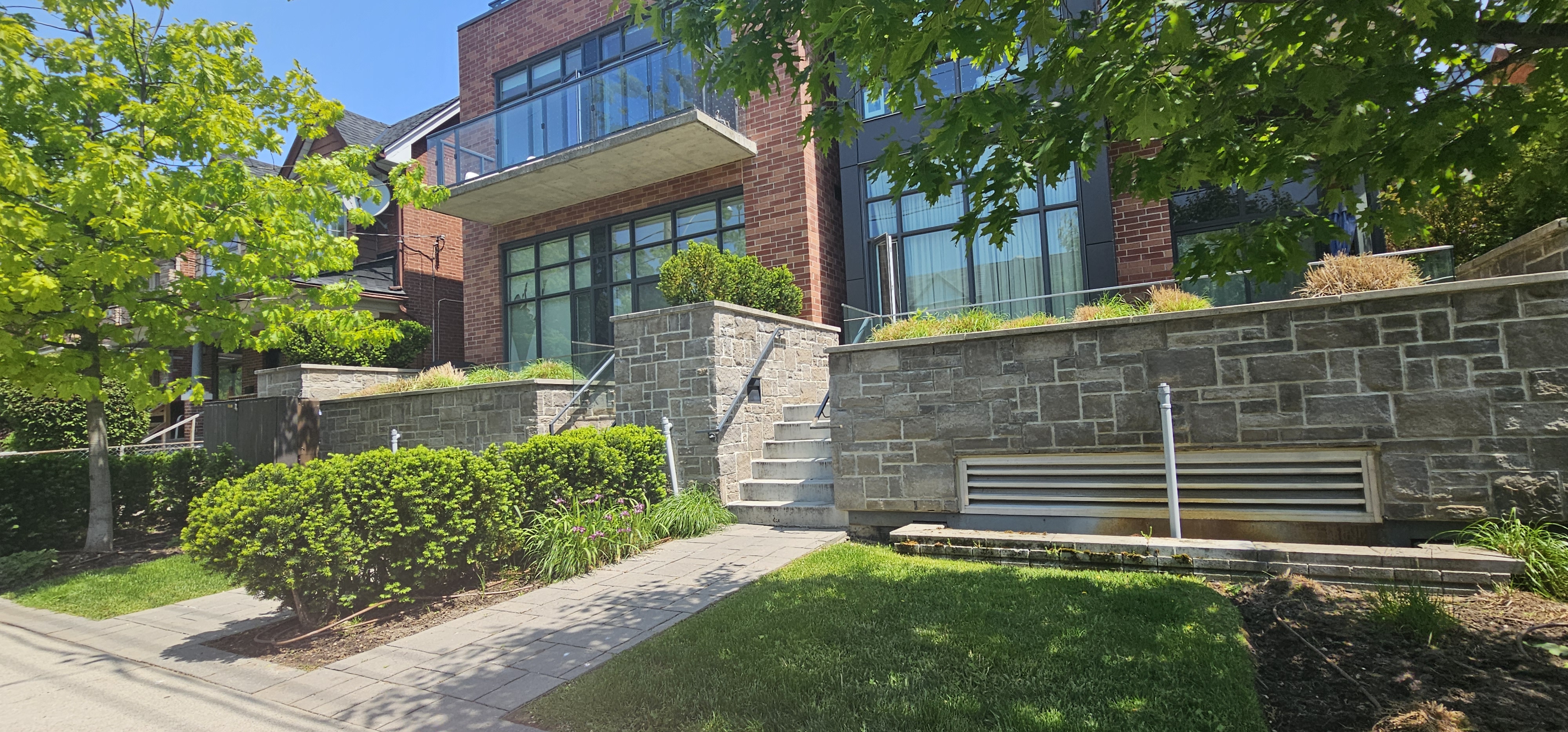 Outdoor entrances to multiple different units with yew hedges and trees